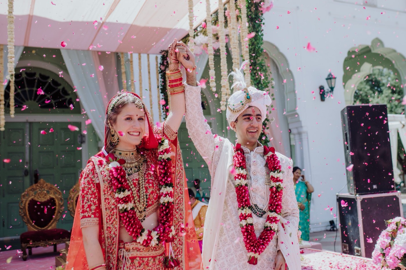 A bride and groom embrace under a shower of rose petals at their EELEGANT EVENTS wedding
