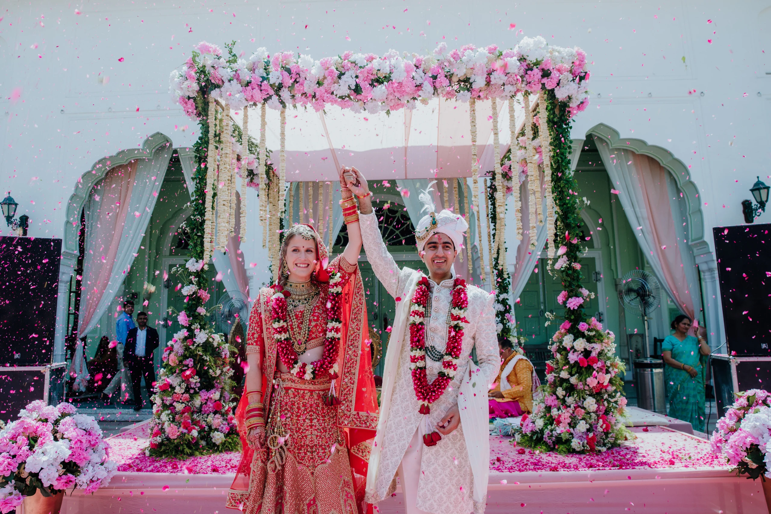 A bride and groom embrace under a shower of rose petals at their EELEGANT EVENTS wedding